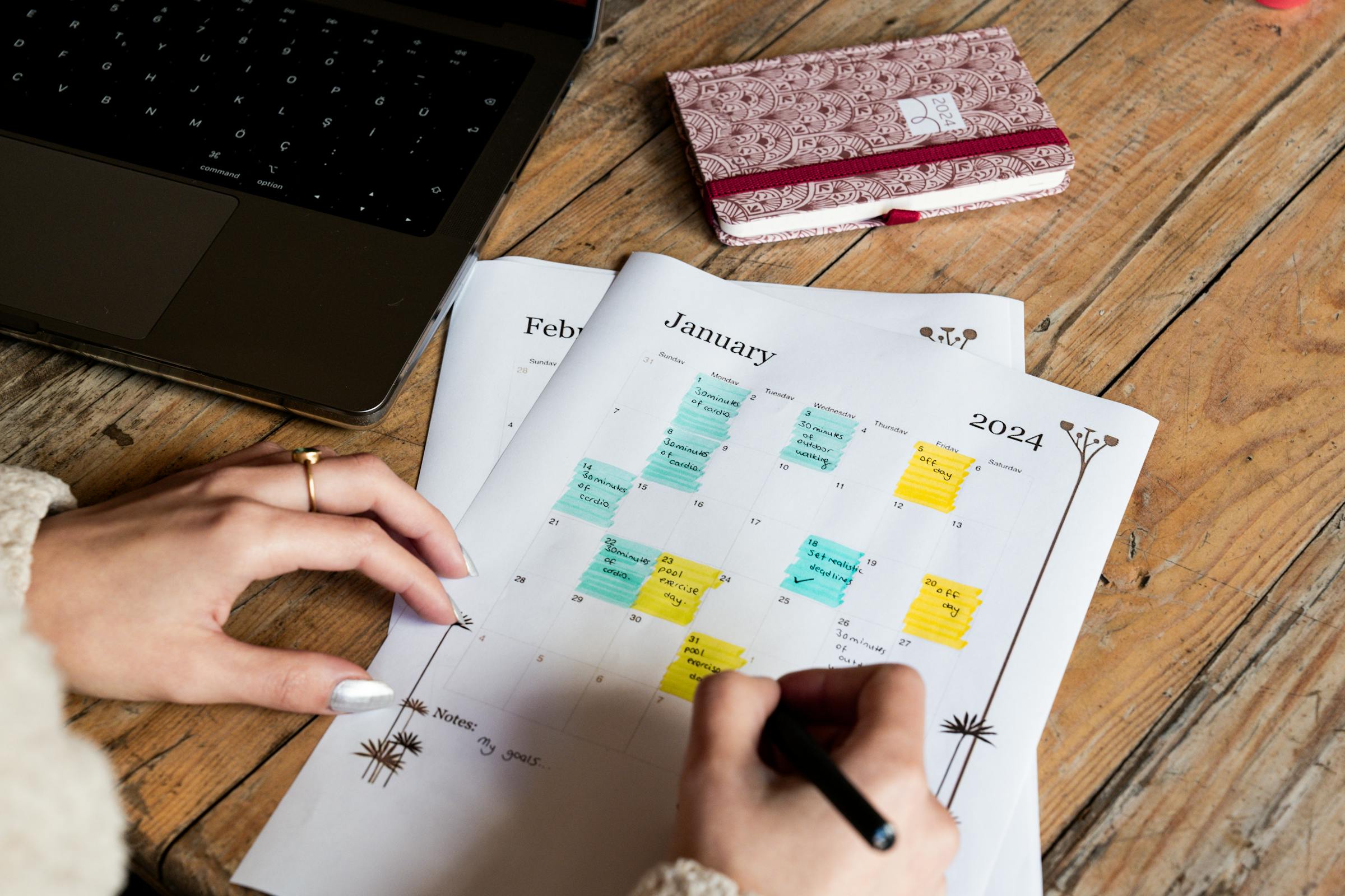 Parent marking accommodation booking dates on a printed calendar during family vacation planning