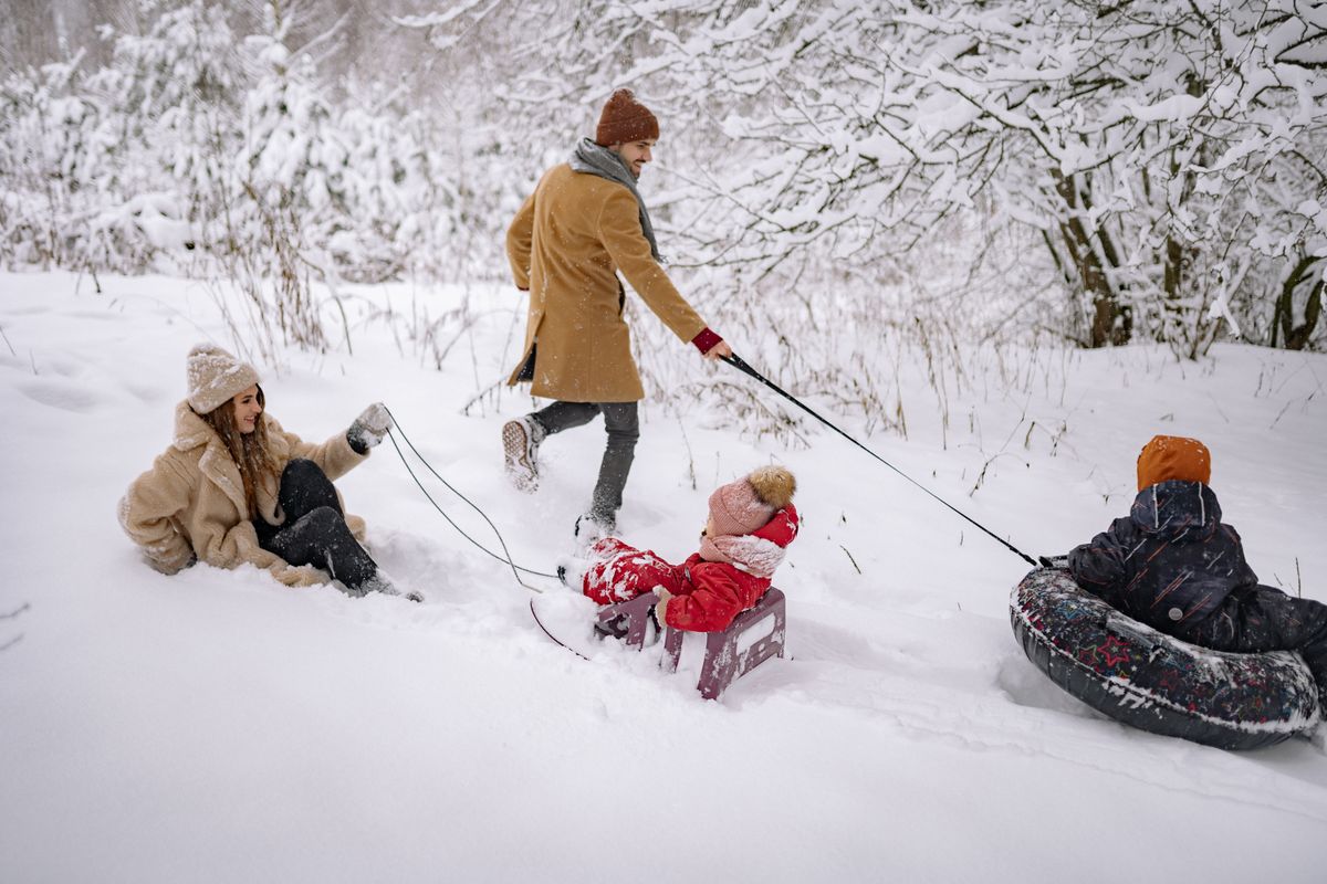 A family of four sledding in the snow, a free winter anchor on a budget family vacation