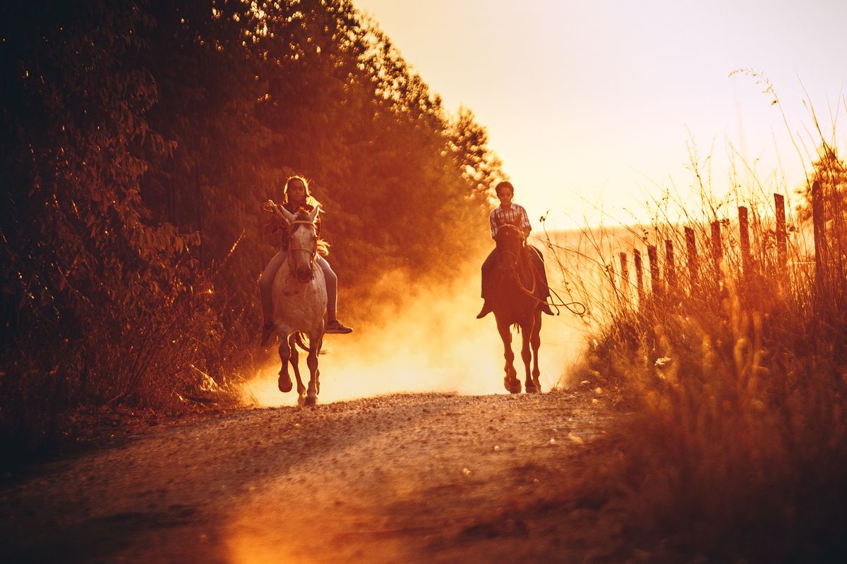 Two kids horseback riding at sunset, the kind of included activity that defines all inclusive resorts in the USA