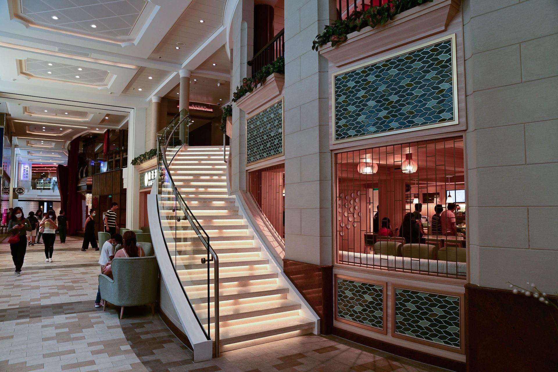 Shopfronts and planting along a cruise ship's indoor promenade deck