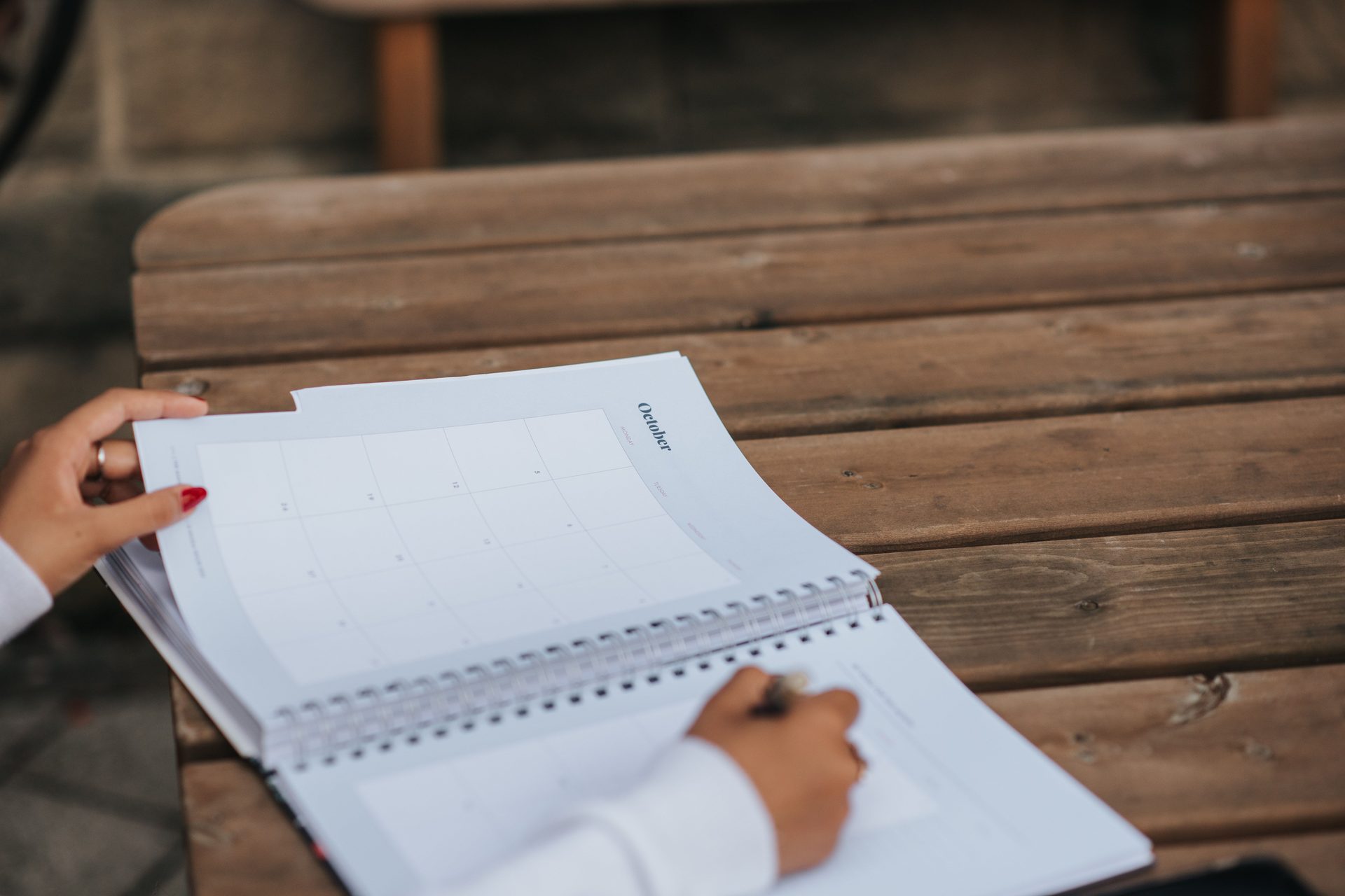 A parent writing sail dates into a monthly planner at a wooden table