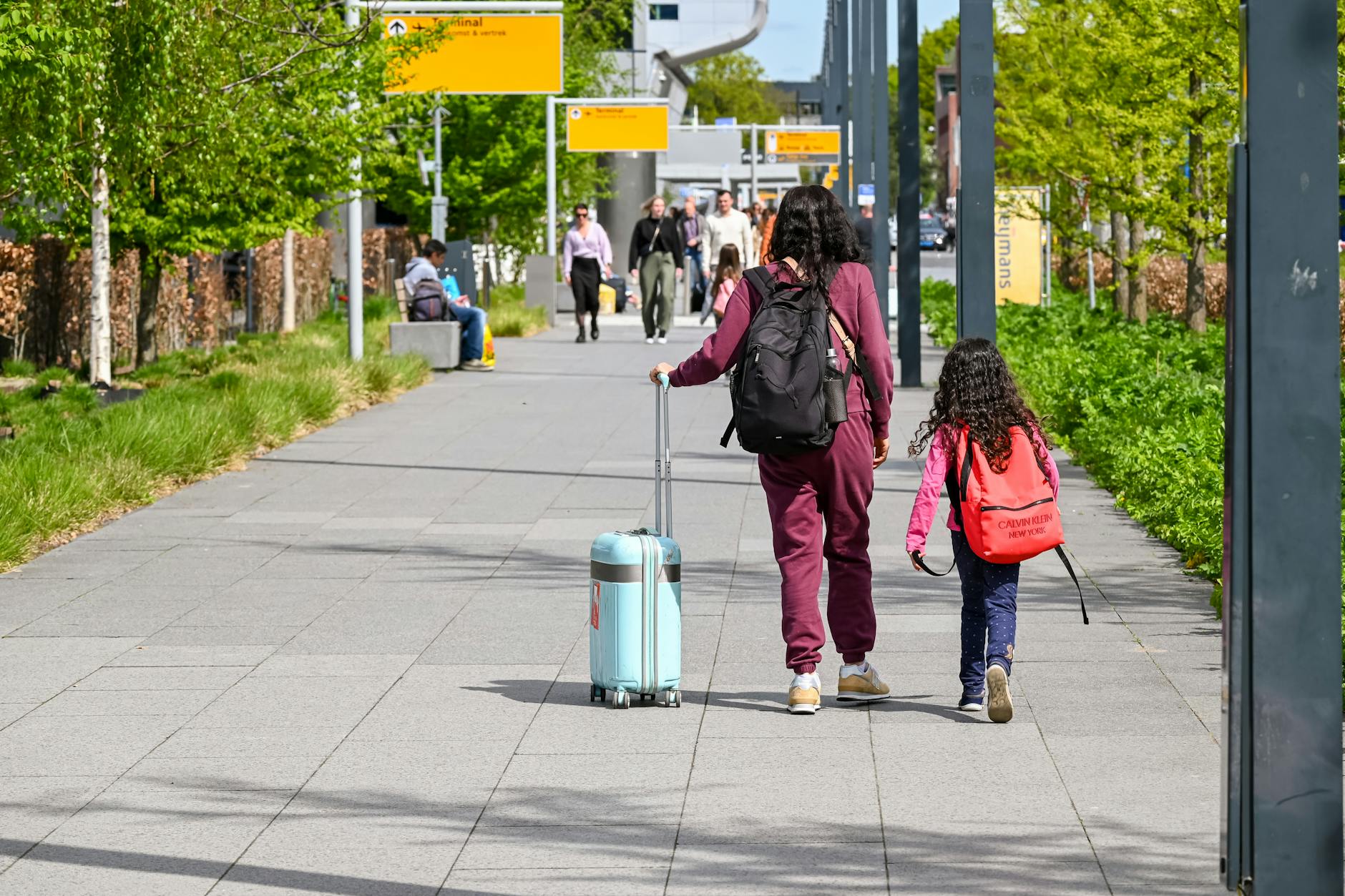 Mother and daughter walking with luggage at airport for family vacation