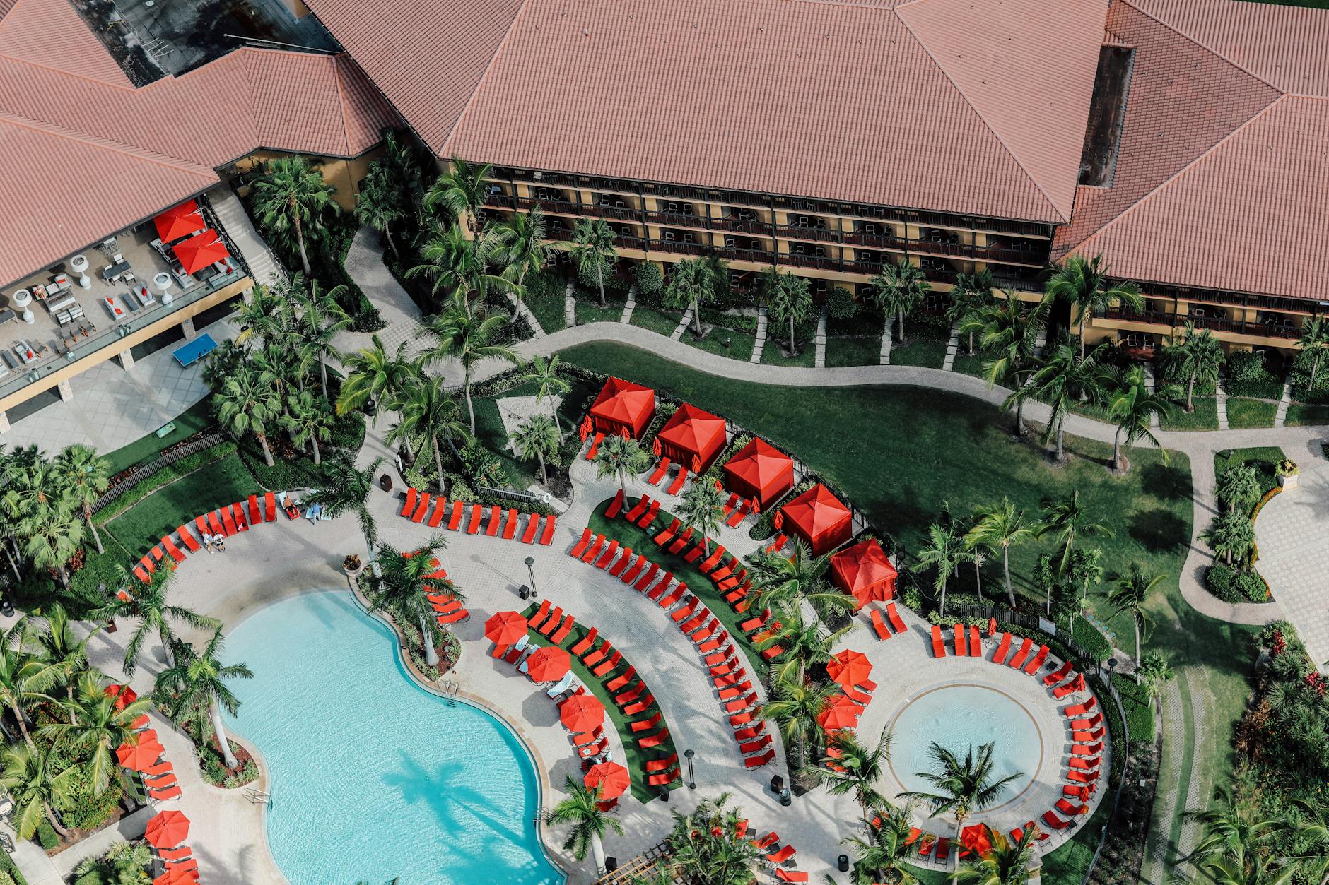 Family-friendly Mexican resort pool deck with palm trees, thatched umbrellas and kids splashing in the foreground