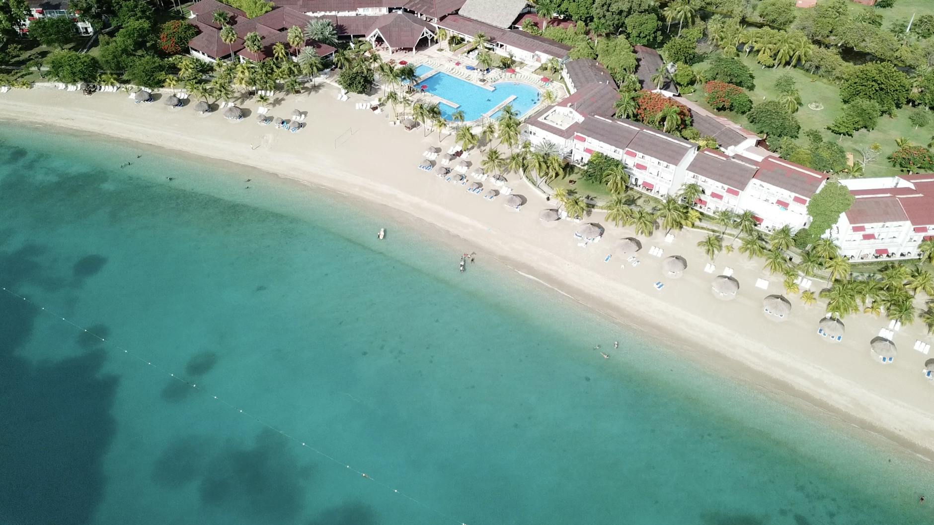 Aerial view of a beachside resort with turquoise waters and tropical greenery in Jamaica