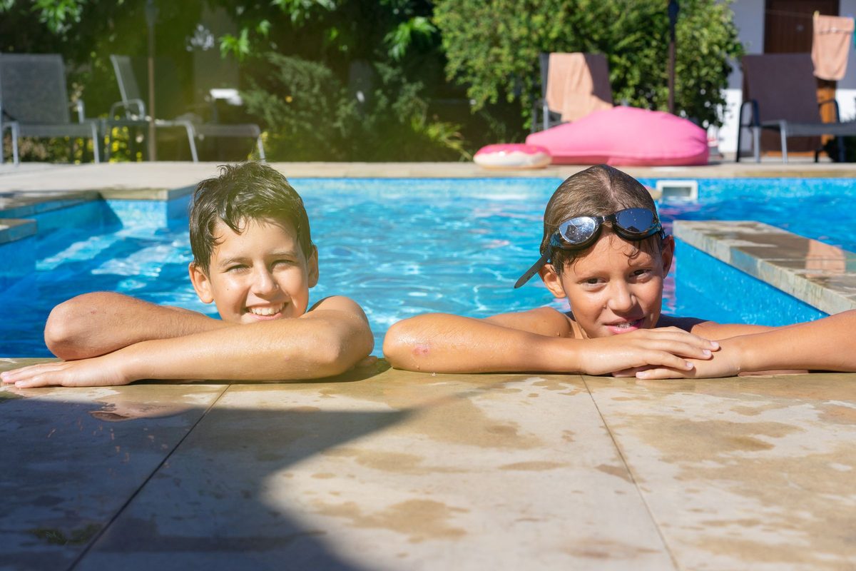 Two young kids playing in a resort swimming pool, the safe-swimming option at Cabo family all-inclusive resorts