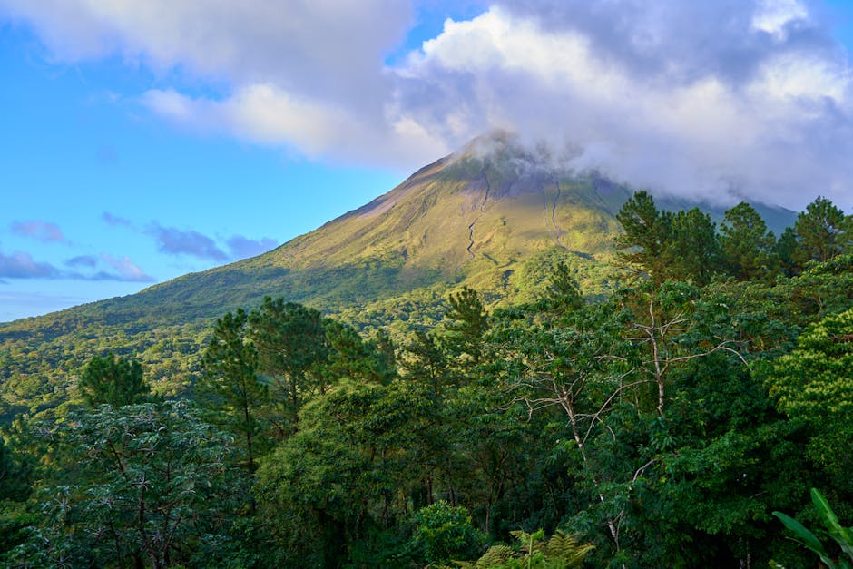 Arenal Volcano rising above lush green Costa Rica landscape under cloudy sky