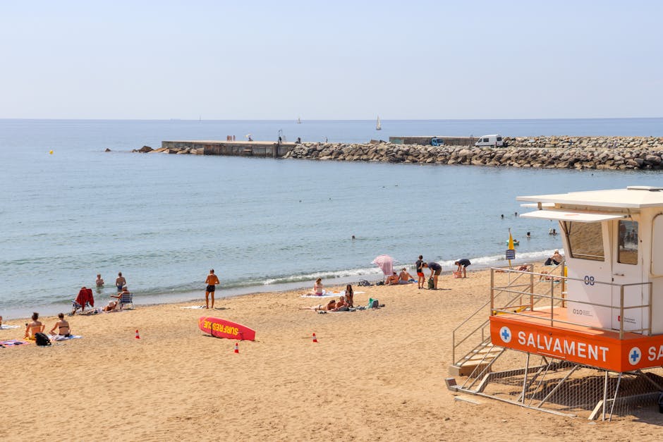 Families and sunbathers enjoying Barceloneta Beach with lifeguard tower in Barcelona