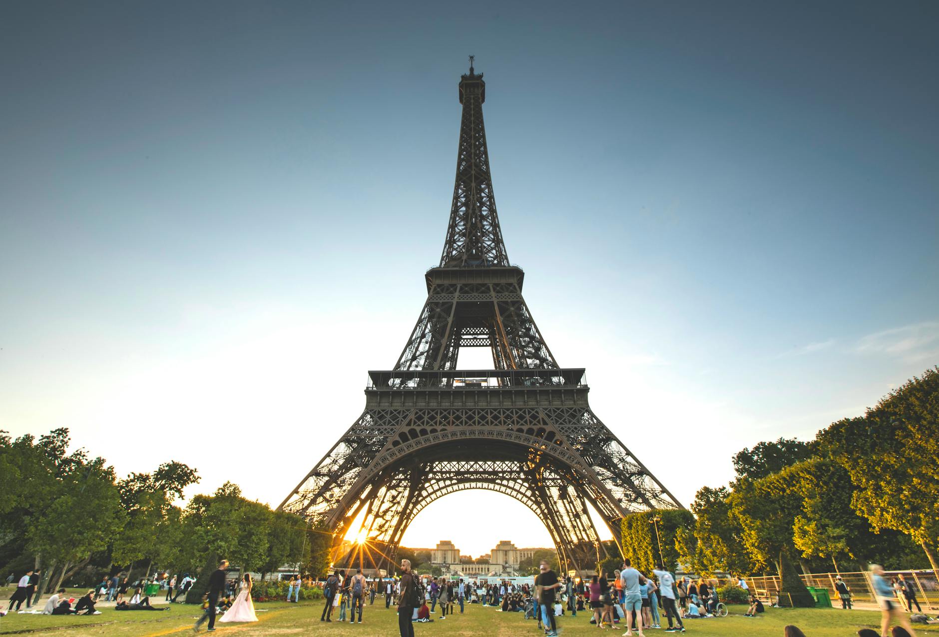 Visitors gathered at the base of the Eiffel Tower on a sunny day in Paris