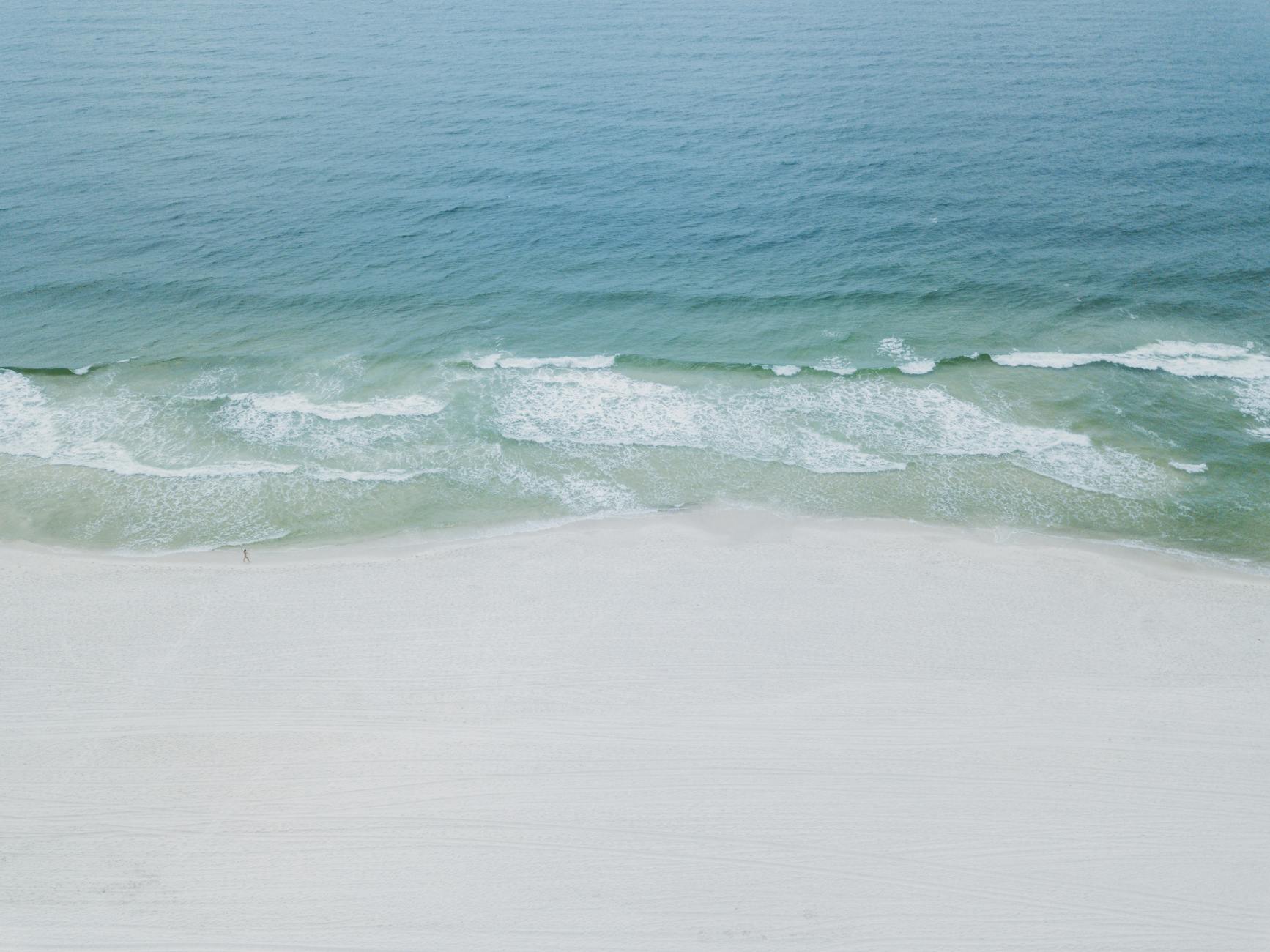 Aerial view of an Alabama Gulf Coast beach with pale sand and clear turquoise water along a quiet shoreline