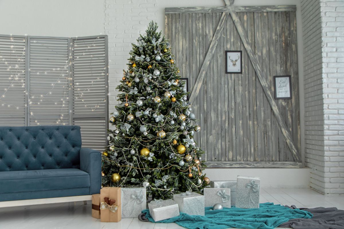 Decorated Christmas tree with gold and silver ornaments and wrapped gifts in a cozy family living room