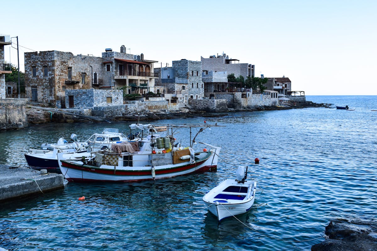 Traditional Greek fishing boats moored in a calm island harbor with blue water