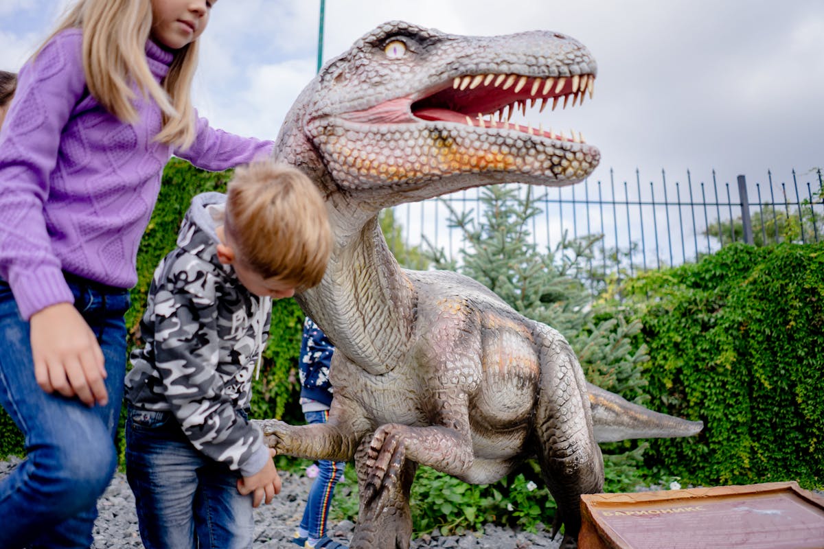 Children playing near a dinosaur exhibit at a museum