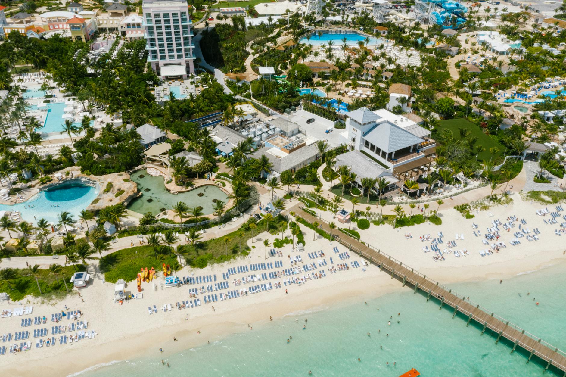 Aerial view of a beach resort with clear turquoise waters and palm trees in the Caribbean