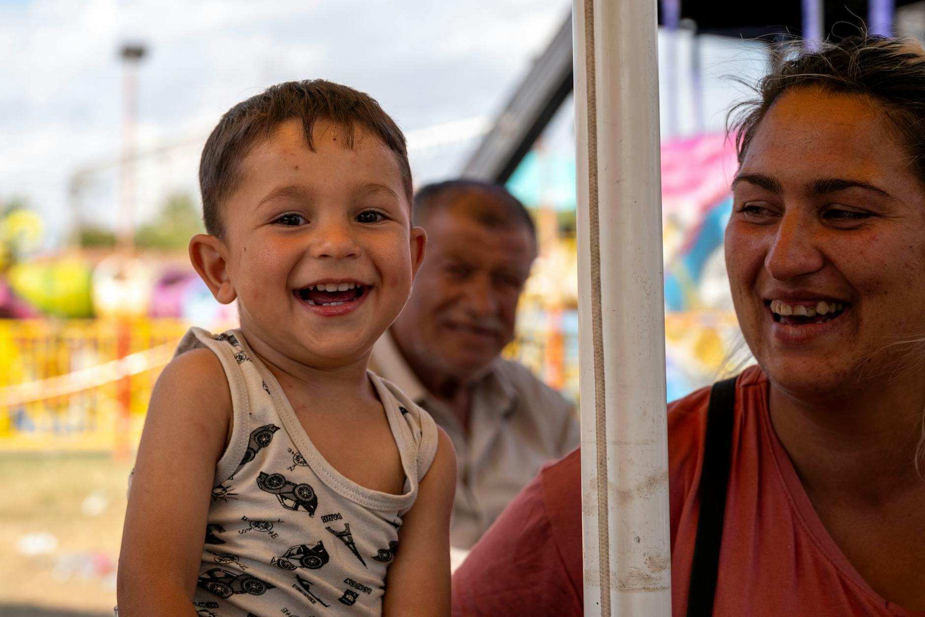Child laughing with family at a summer amusement park