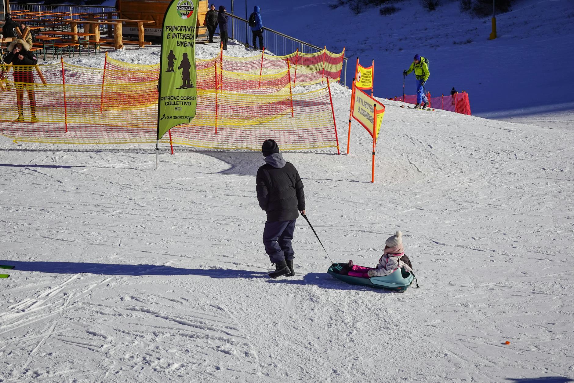Parent pulling child on a sled at a snowy winter ski resort