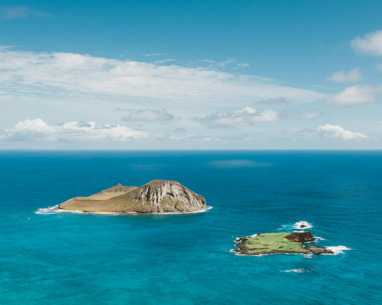 Hawaiian coastline aerial view with turquoise water and offshore island for the Big Island vs Maui vs Oahu family decision