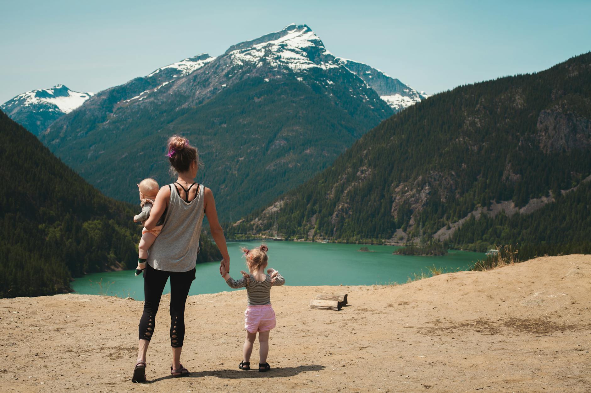 Mother and children enjoying a scenic mountain lake view during a sunny family hike