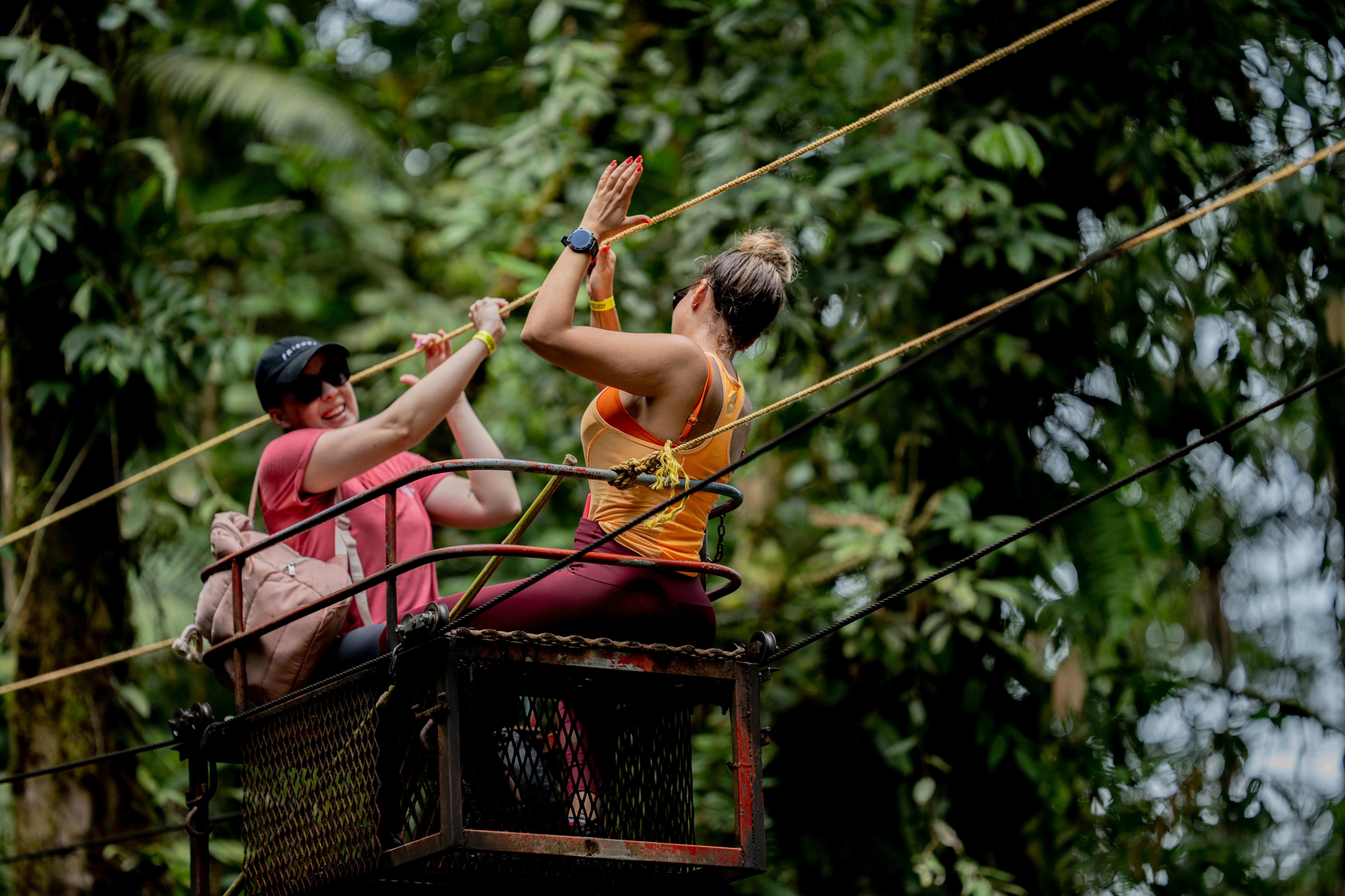 Two people zip-lining through lush Costa Rican jungle canopy near Bajos del Toro