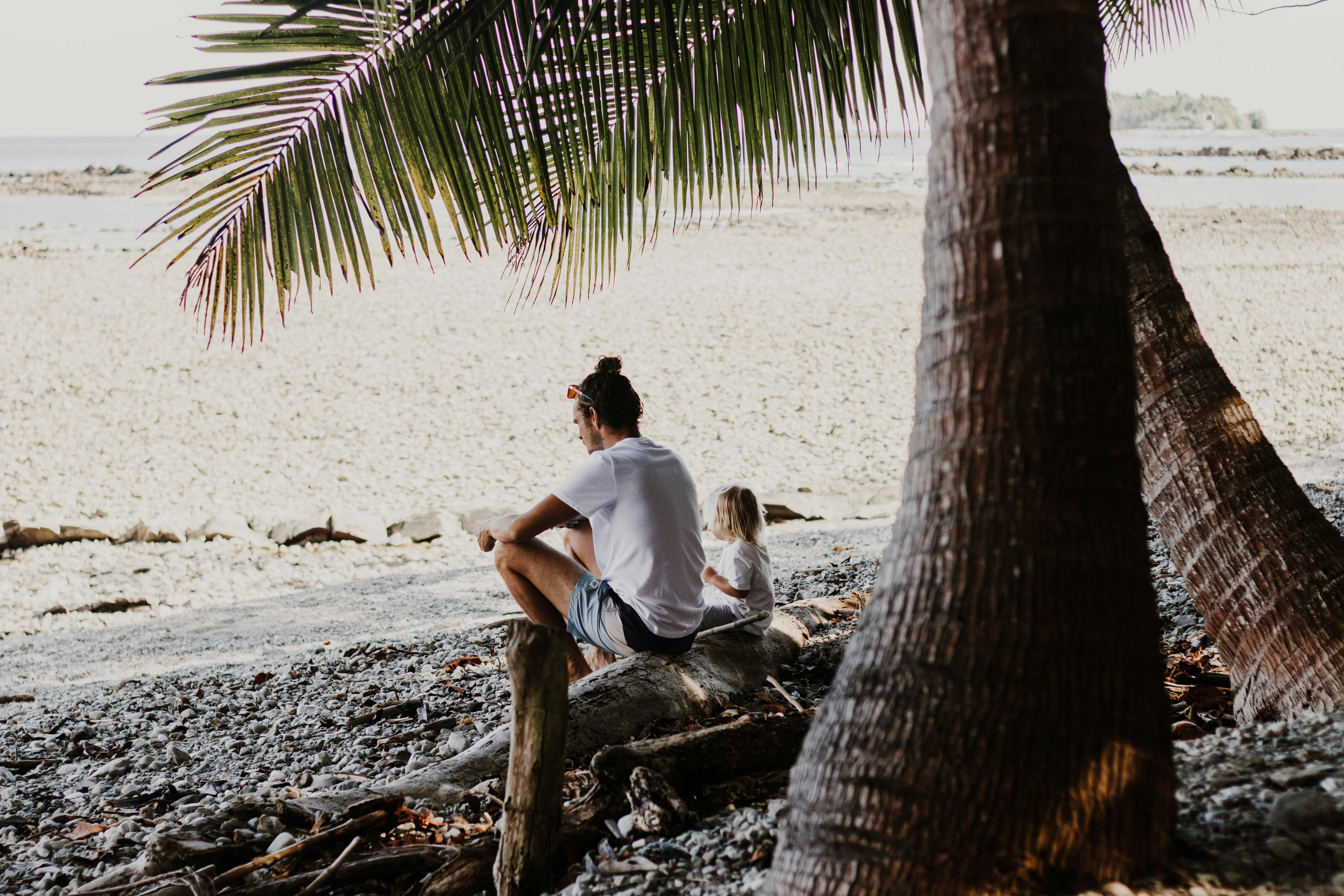 Parent and child relaxing under palm trees on a Costa Rica beach