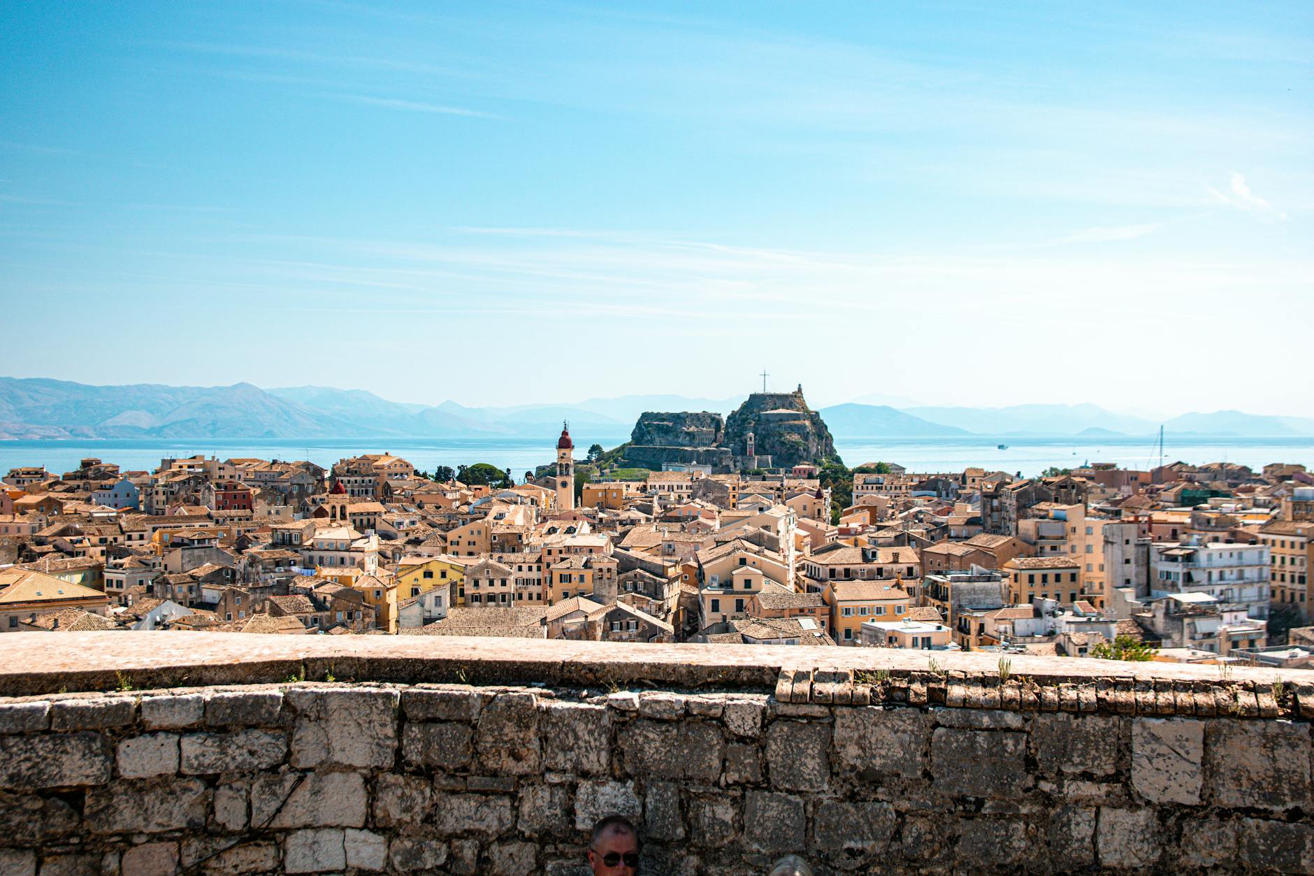 Historic fortress and waterfront buildings in Corfu Old Town under a clear blue sky