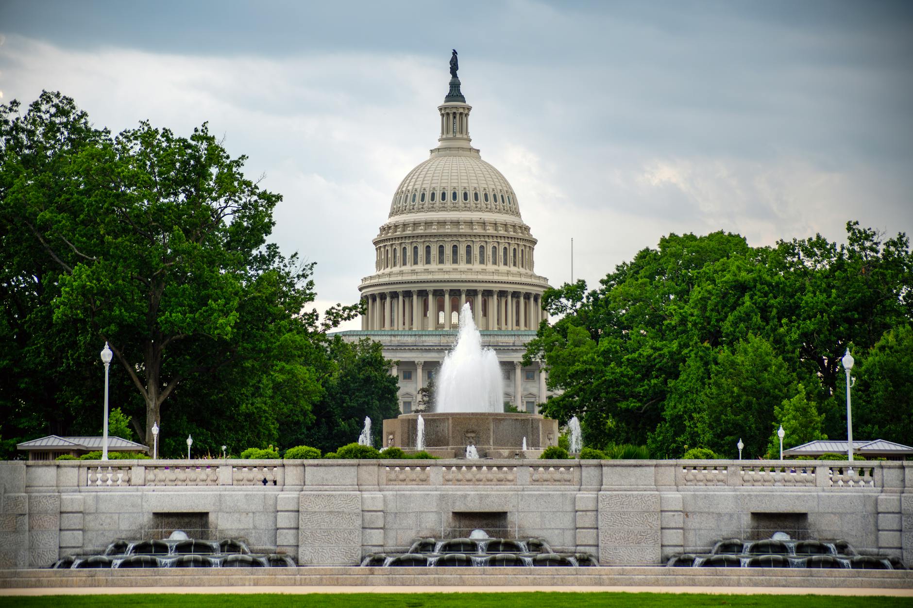 US Capitol Building with fountain in foreground under dramatic cloudy skies