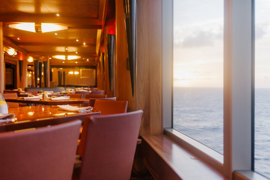 Elegant dining tables set up on a cruise ship with ocean views at sunset