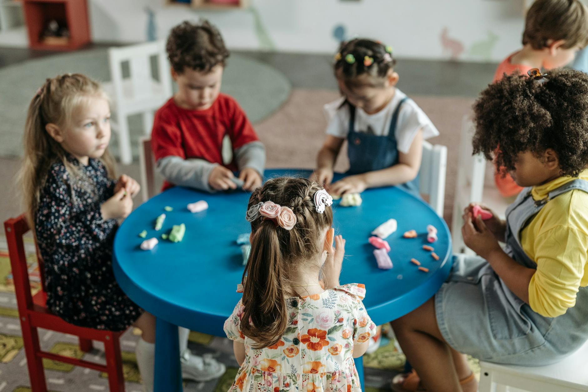 Group of preschool children playing together with crafts at a colorful activity table