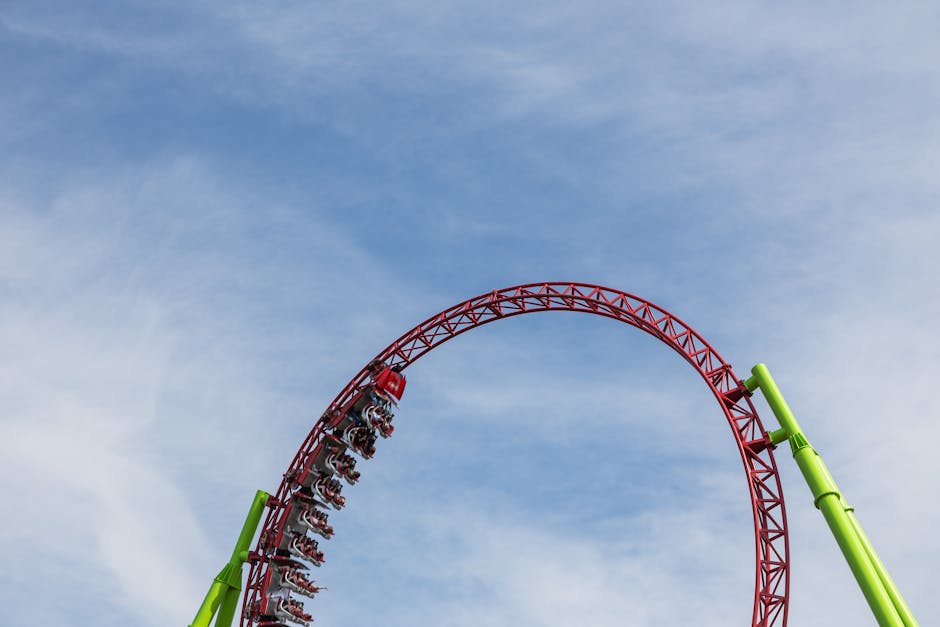 Riders on a looping roller coaster against a blue sky at a theme park