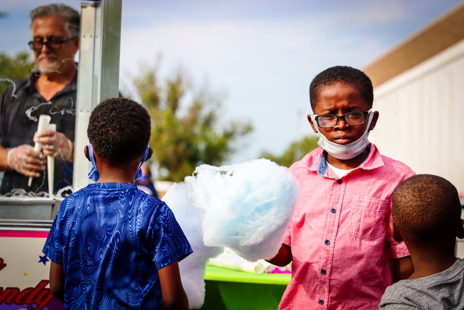 Children savoring cotton candy at a vibrant outdoor family event