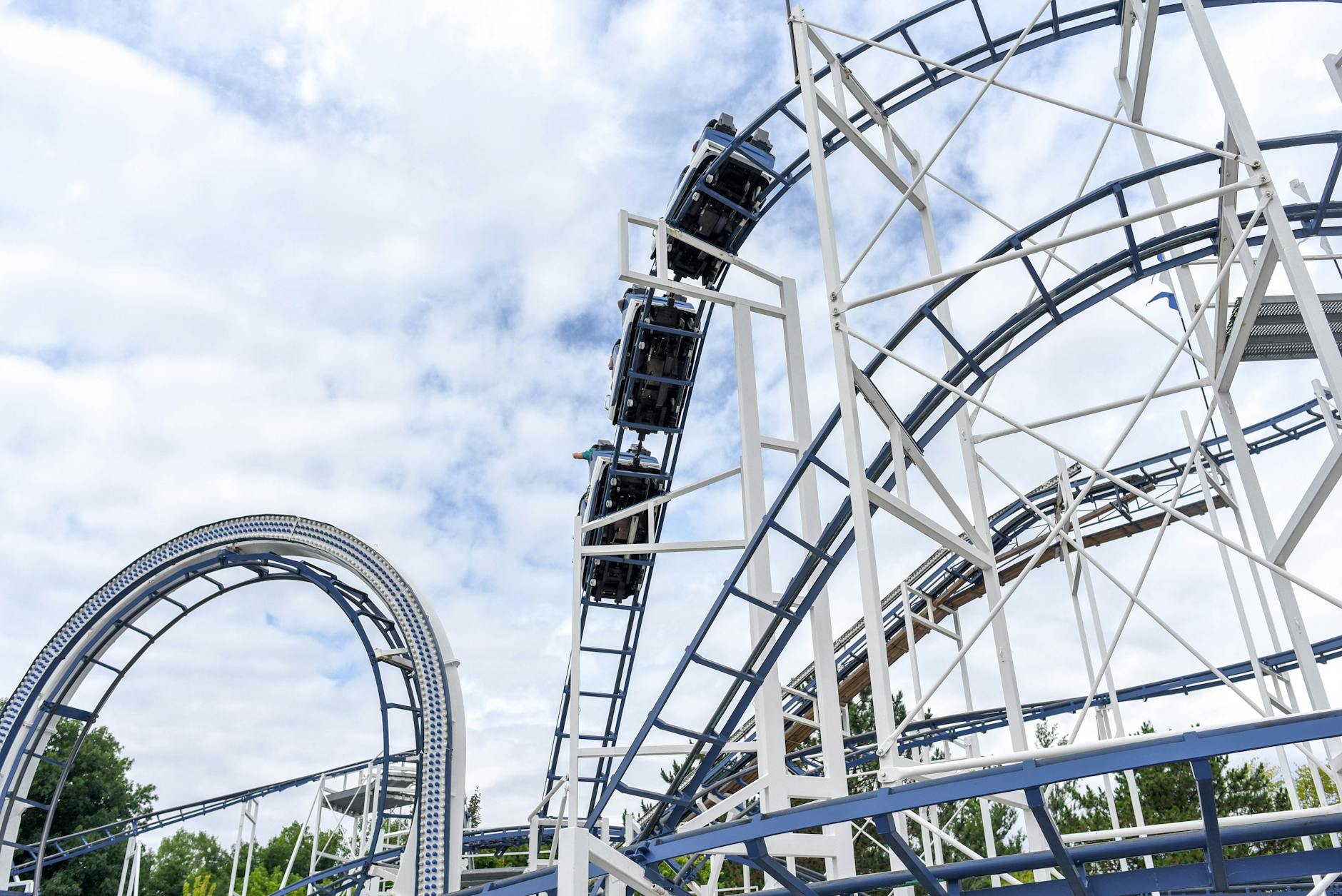 Steel roller coaster with loops at an outdoor amusement park under a clear blue sky
