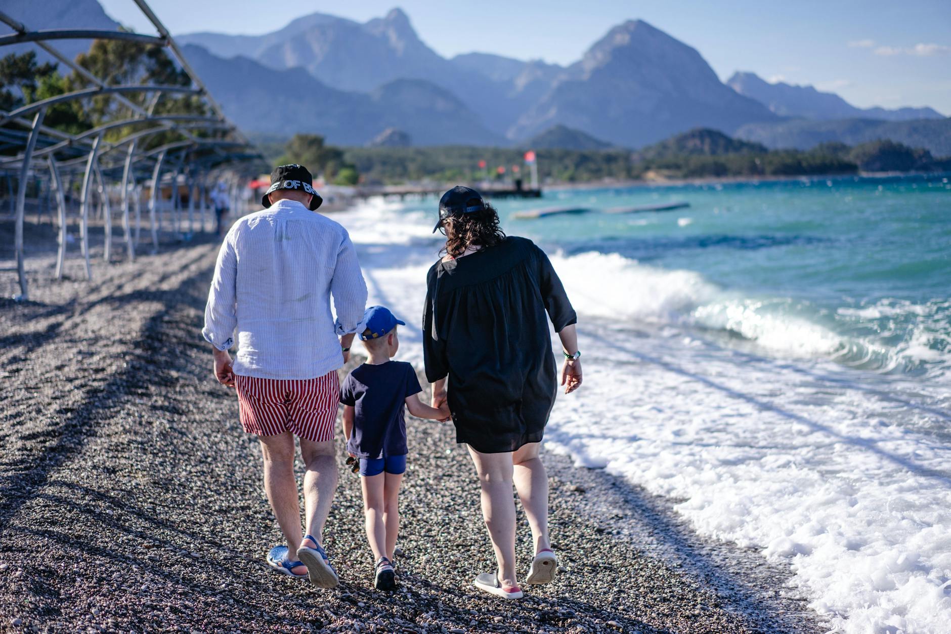 Family walking along Kemer beach in Turkey with mountains behind, a family holidays to Turkey scene