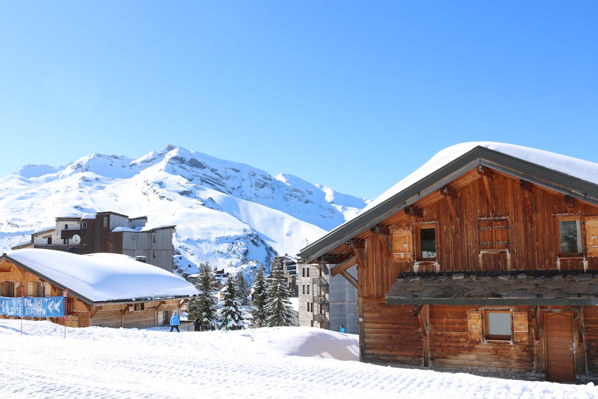 Snowy alpine village with rustic wooden cabins at dusk during a family ski holiday