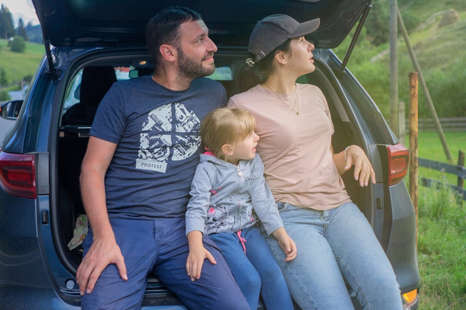 Family sitting together in car trunk during an outdoor adventure road trip