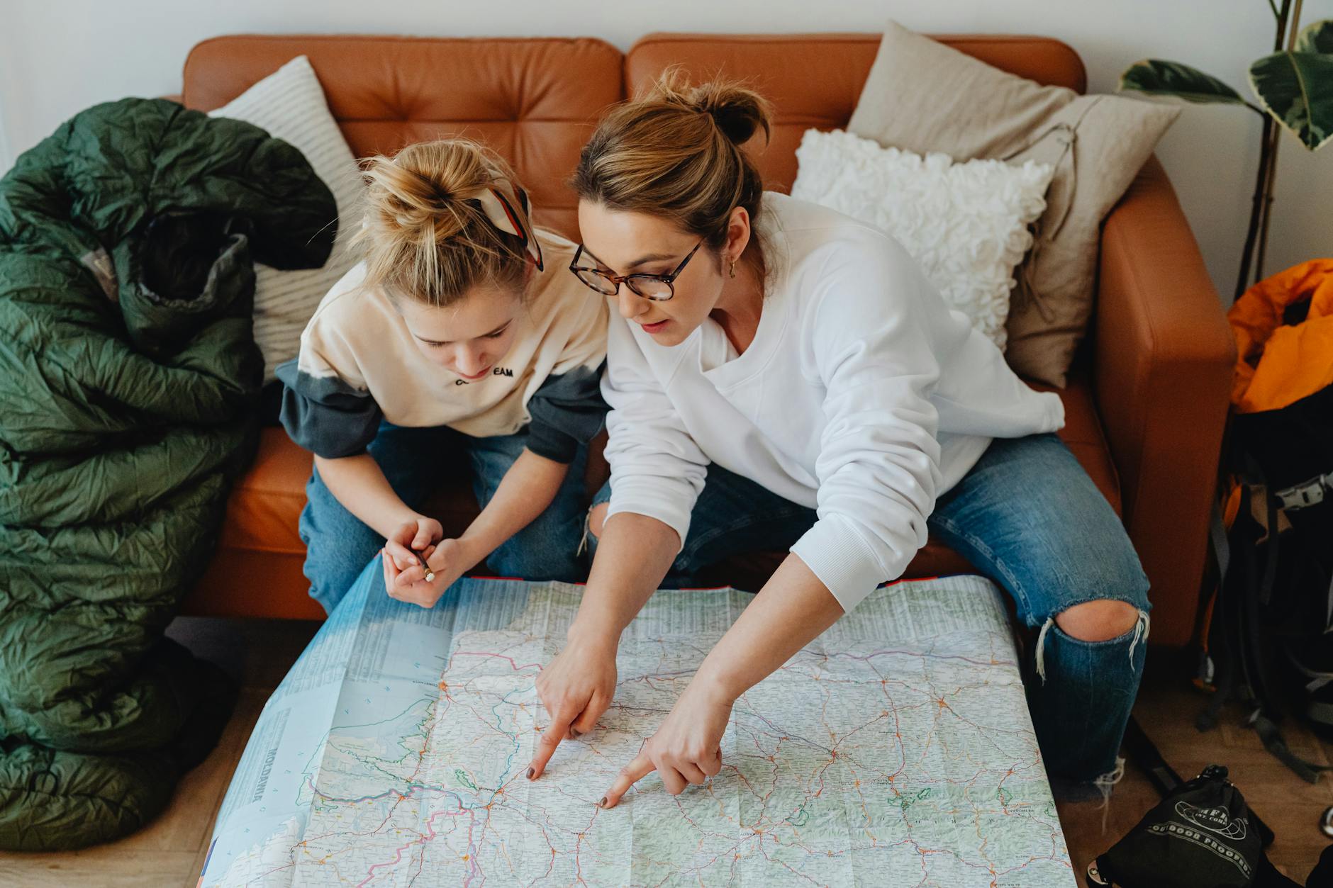 Mother and daughter planning a family trip with a paper map deciding how many days to book