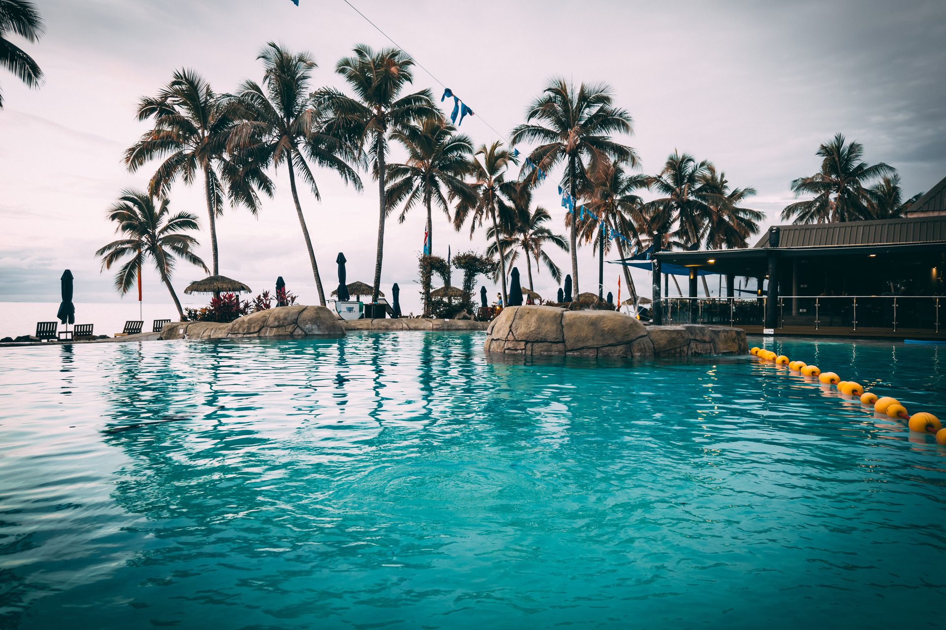 Palm-lined pool at a Fiji resort, where kids club and meal rules change what a family pays