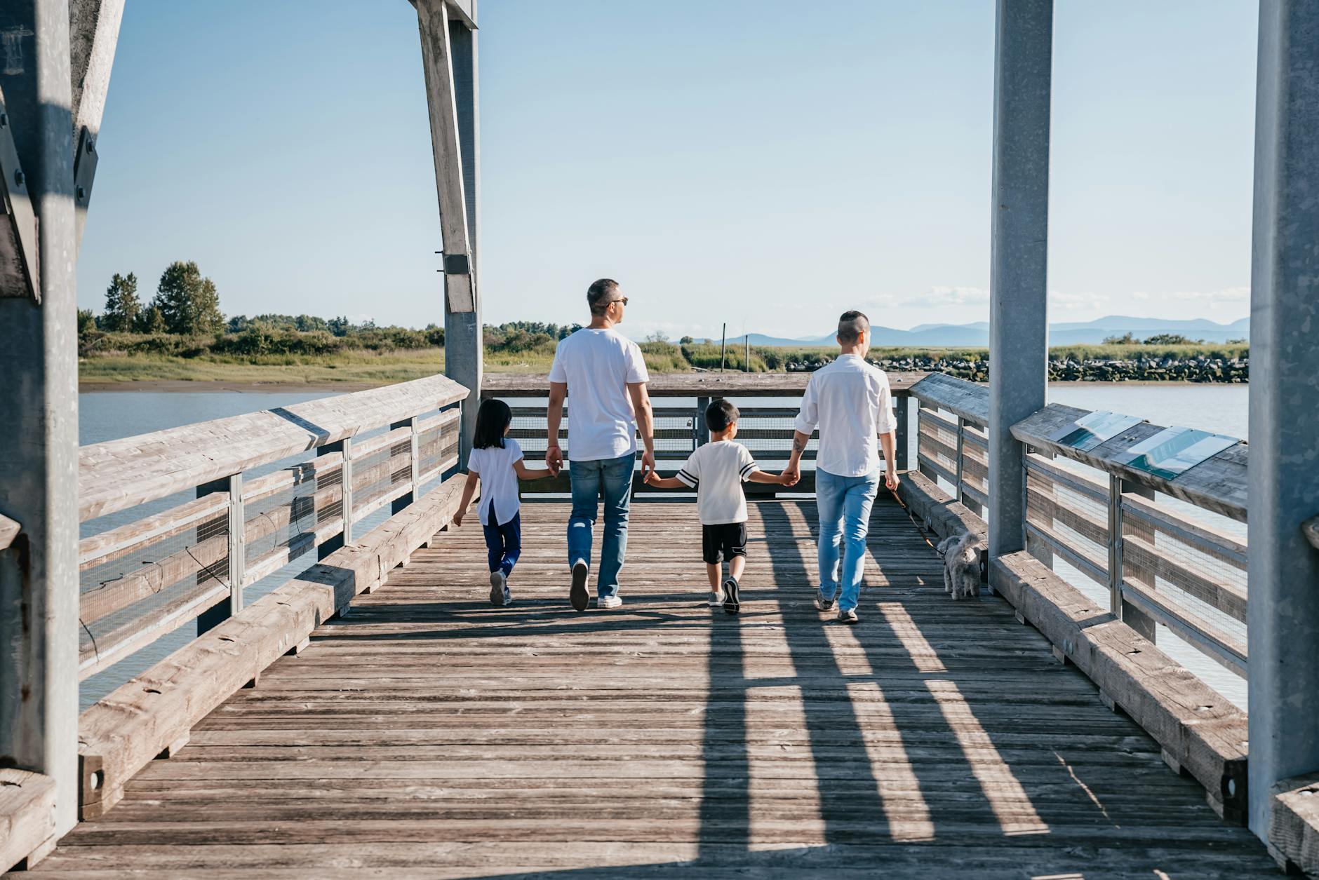 Family walking hand in hand along a sunny boardwalk