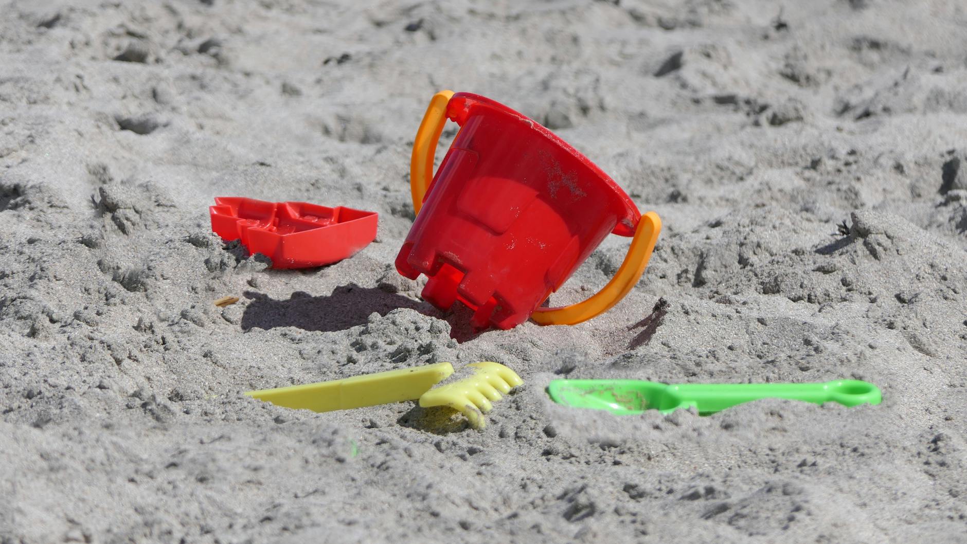Colourful beach bucket and toys on sandy shore during a family holiday