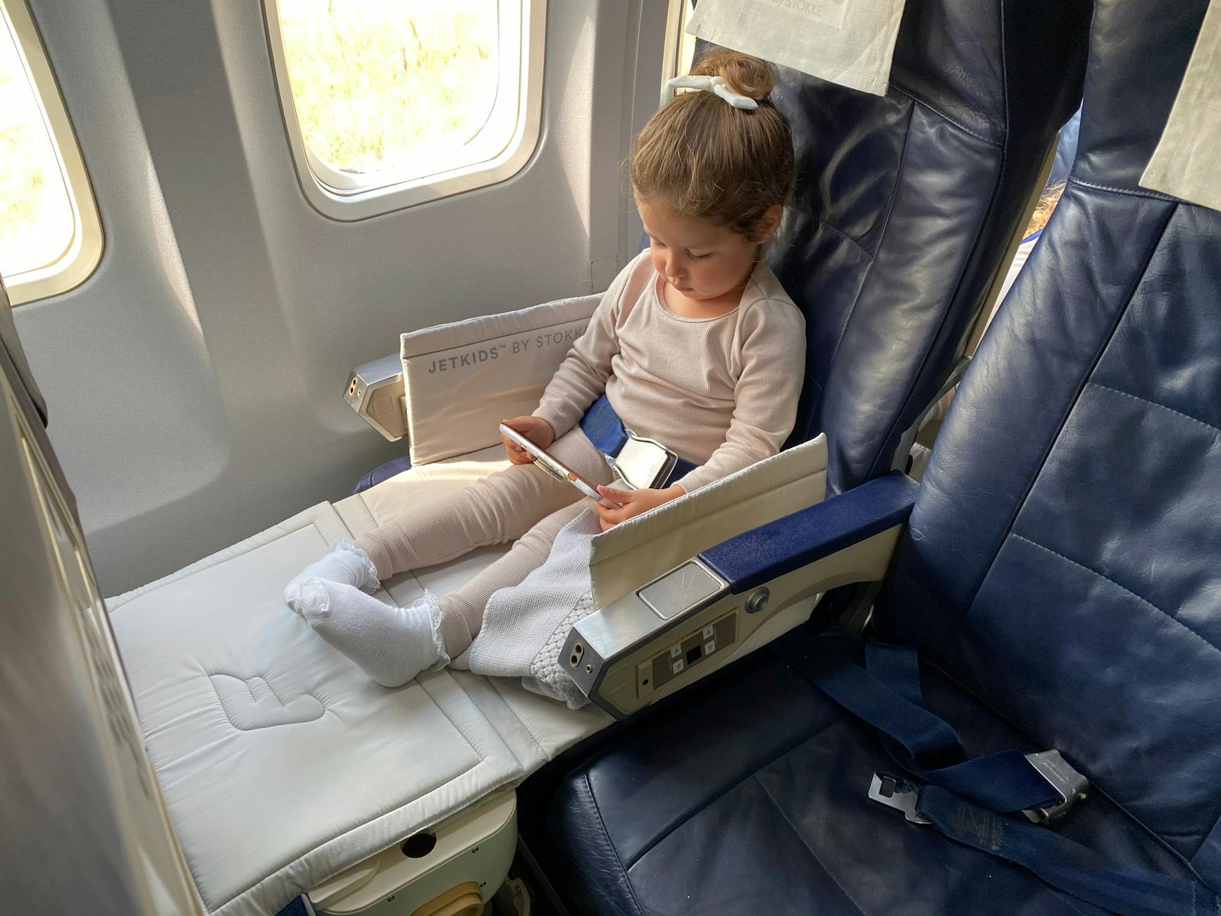 Young girl looking out airplane window during flight
