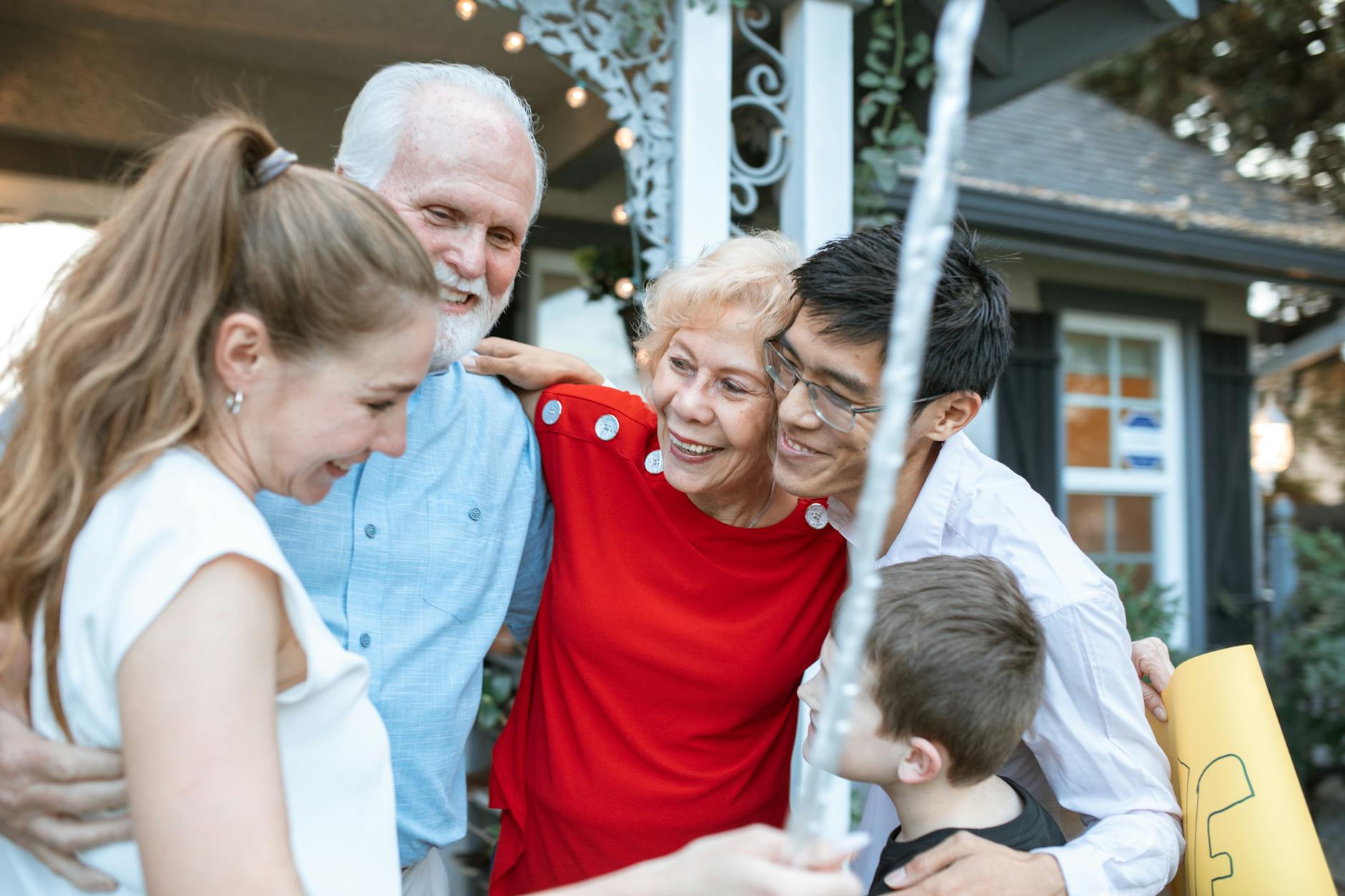 Extended family of different ages hugging in a group outdoors