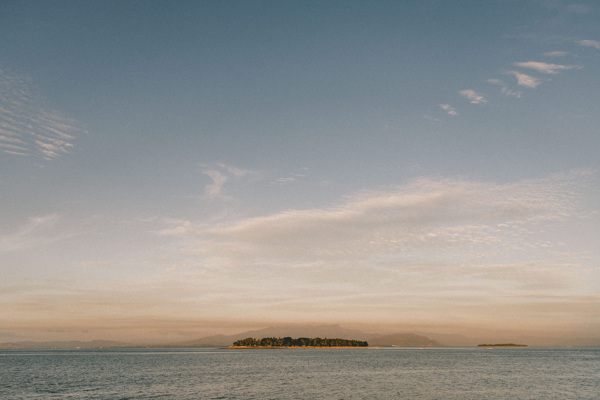 A small island ringed by reef at sunrise in Fiji, the Fiji side of this family comparison