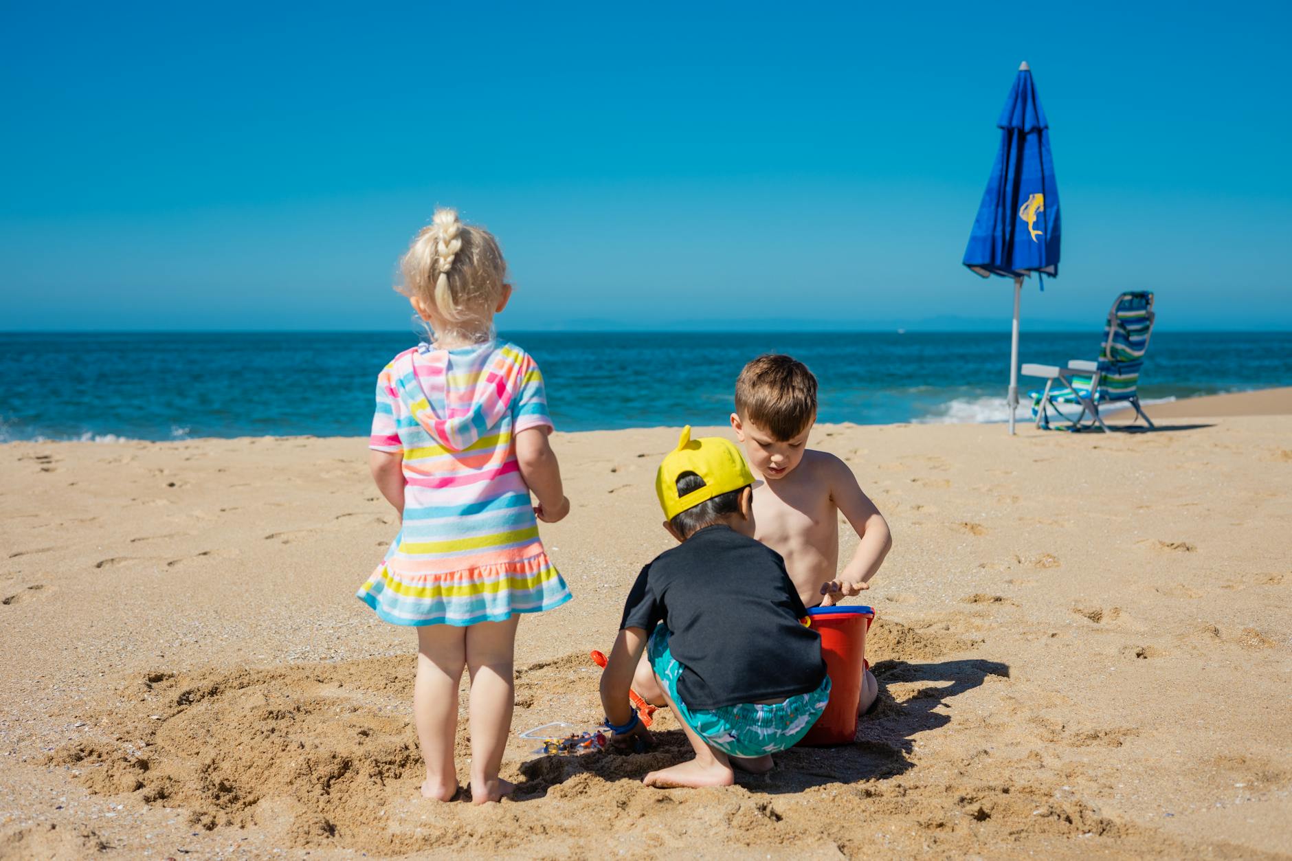Children playing on the beach with sand toys and umbrellas on a sunny day