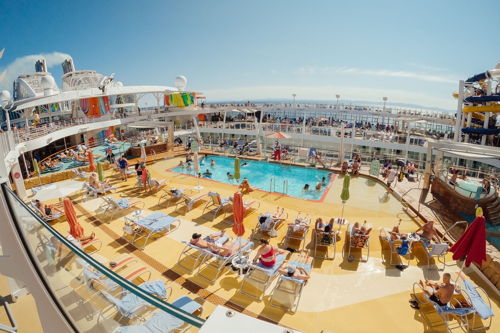 Families relax on sun loungers around a cruise ship's pool deck