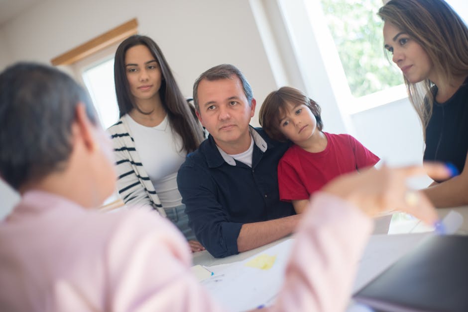 A family of four planning together during an indoor consultation, discussing vacation options in a bright room