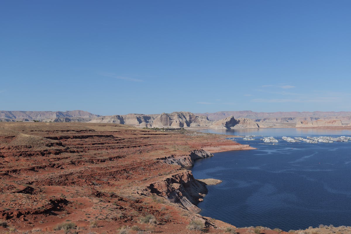 Red rock formations rising from Lake Powell waters with canyon walls in the background