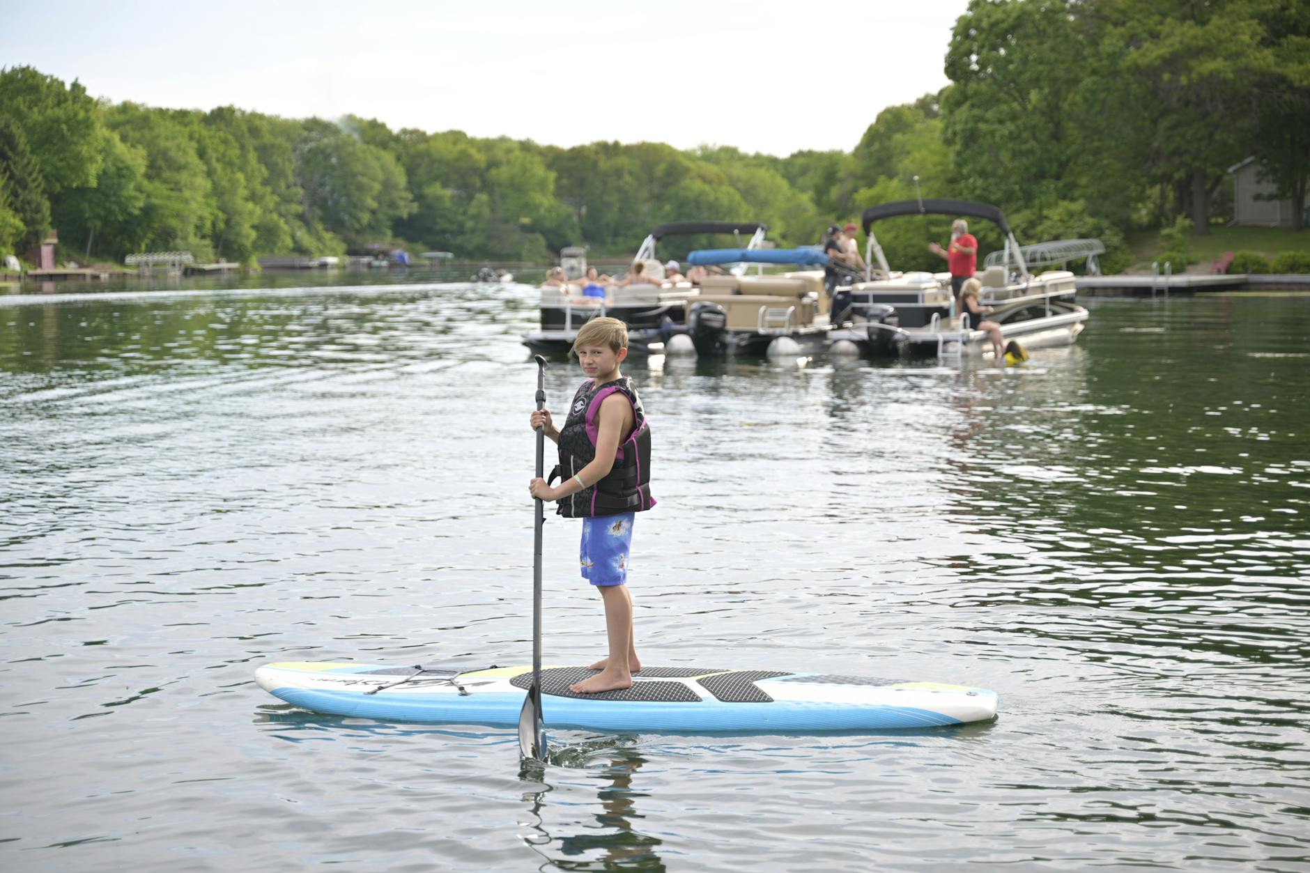 Child paddleboarding on calm lake water on a sunny summer day
