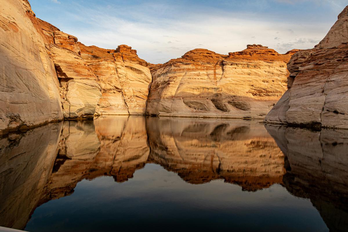 Dramatic view of Lake Powell's iconic red rock canyon walls towering above brilliant turquoise waters, showcasing the stunning desert reservoir landscape