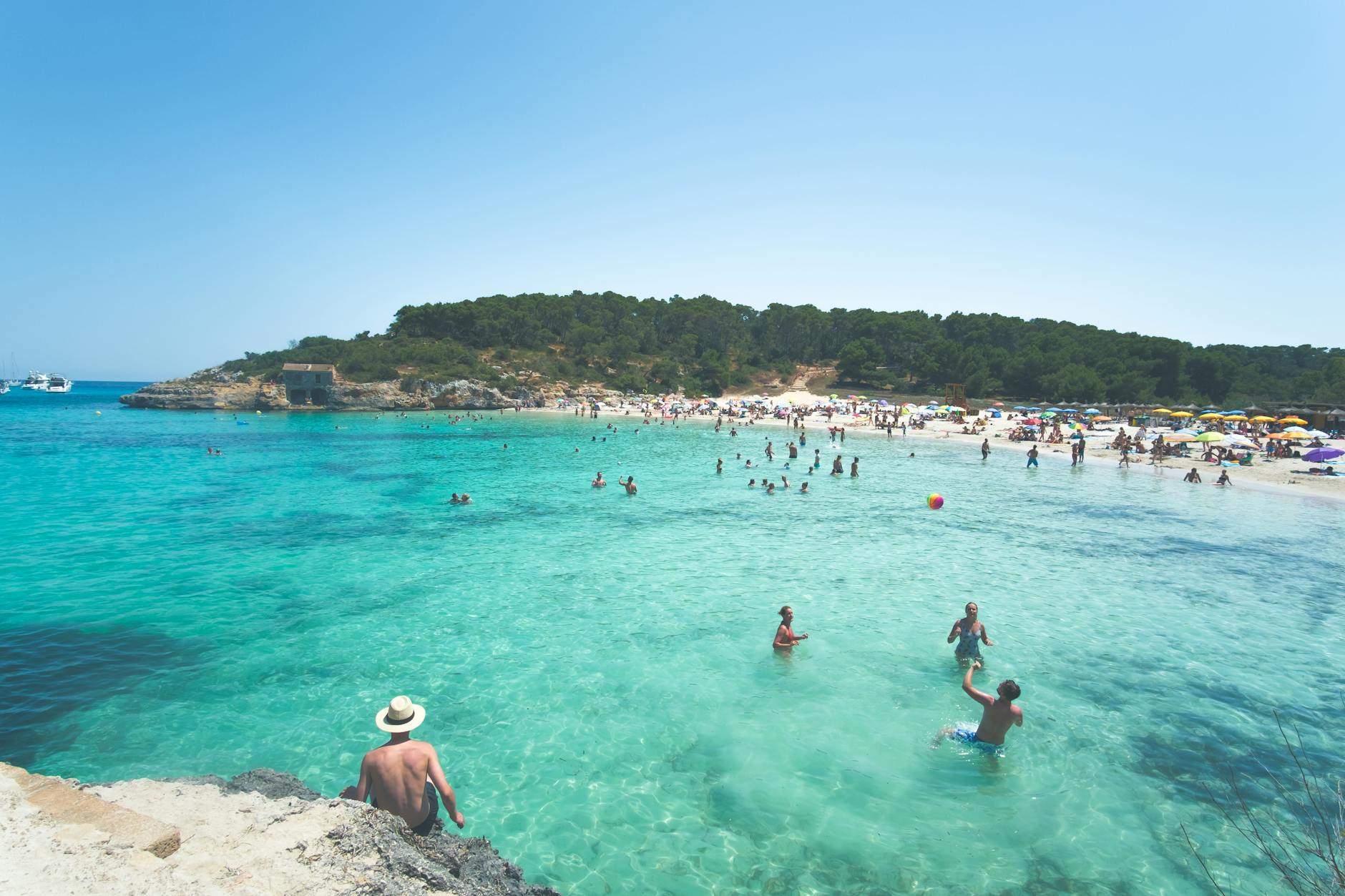 Families swimming in clear turquoise water at a Majorca beach cove