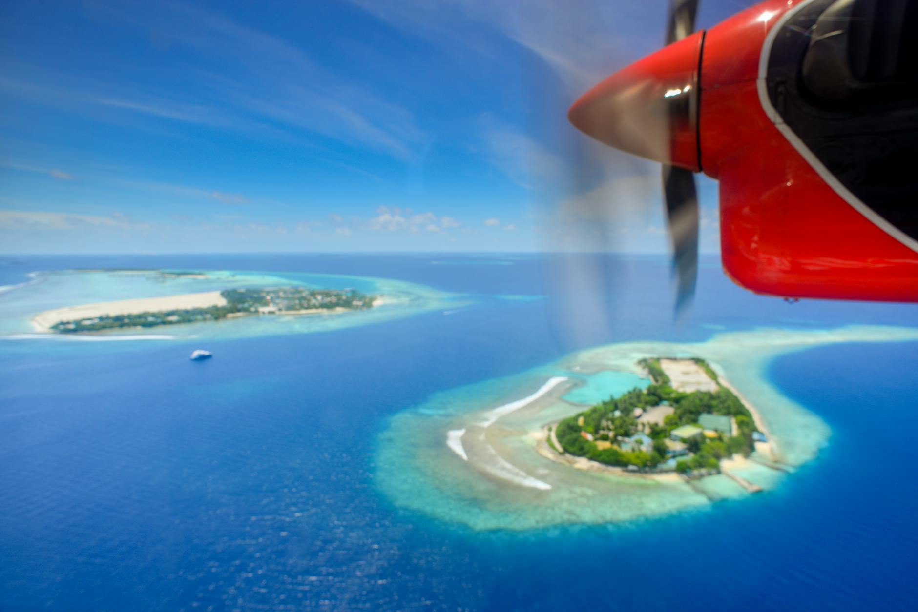 Small seaplane on Maldives water with tropical island resort in background