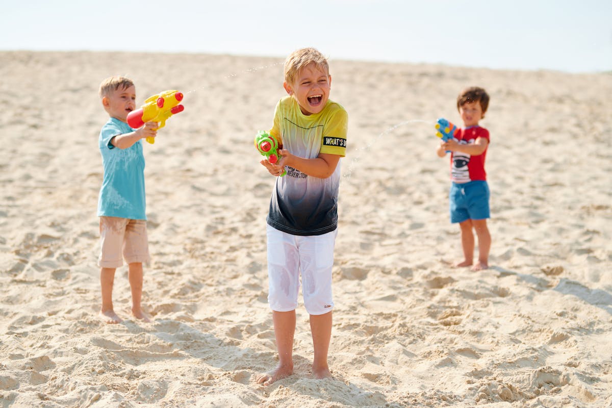 Children playing with water guns on a sunny beach