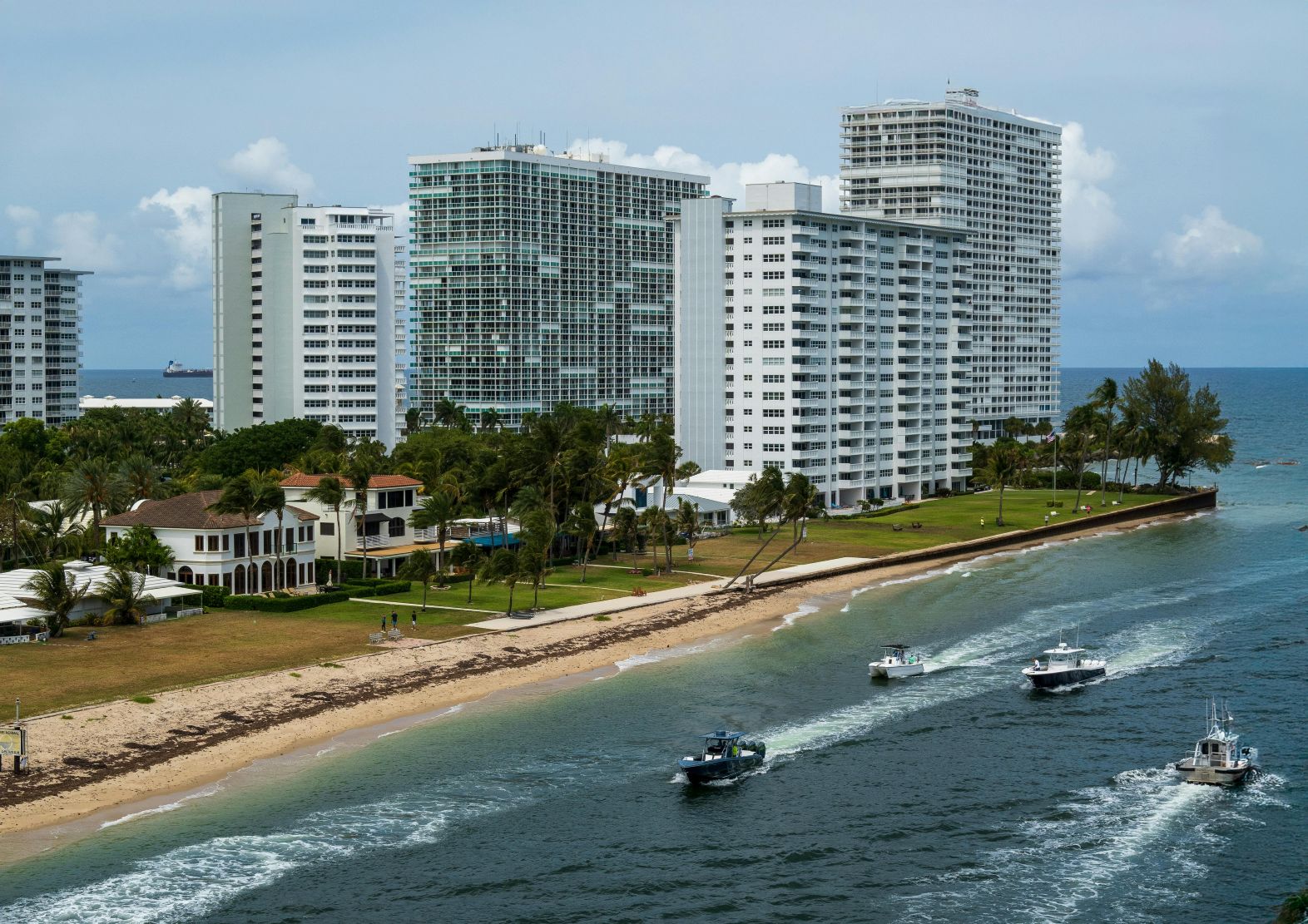 Fort Lauderdale beach with pristine golden sand, calm azure waters, swaying palm trees, and beachfront properties along the coastline